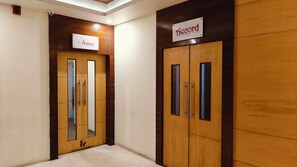 A hallway with two wooden doors, one labeled "Aroma" and the other "Accord Board Room." - Alps Residency-A Bergamont Hotel (Krishnagiri)