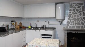 A compact kitchen with white cabinets, a granite countertop, a built-in dishwasher, and a stone-patterned backsplash. - 9, Cimo da aldeia (Aldeia de João Pires)