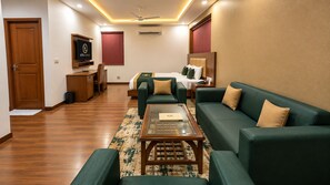 A hotel room with a sofa set, a bed, a television, and a desk.
