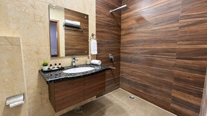 A modern bathroom with a marble sink, wooden vanity, and a shower area with a wooden wall. - Hotel Lohmod (New Delhi)