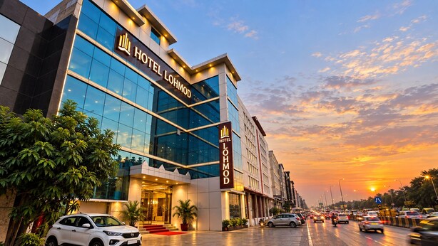 A modern hotel building with a prominent entrance and a clear sky. - Hotel Lohmod (New Delhi)