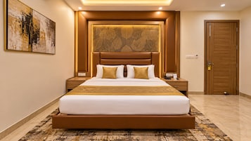 Una camera d'albergo con un letto grande, una testiera decorata con motivi a foglia, un comodino con il telefono e una porta con serratura.