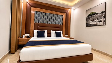 Een hotelkamer met een groot bed, een houten hoofdbord en een schilderij aan de muur.