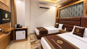 Een hotelkamer met twee bedden, een bureau met een koelkast, een televisie en airconditioning.