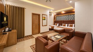 A hotel room with a sofa set, a television, a desk, and a bed. - Hotel Lohmod (New Delhi)