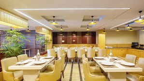 Un restaurant doté de nombreuses tables et chaises, de lambris en bois aux murs et d’un éclairage suspendu.