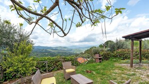 An outdoor seating area with wicker furniture and a view of the countryside.