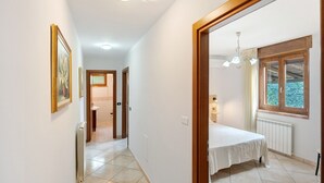 A bedroom with a bed, a window with a view, a radiator, and a door leading to another room.