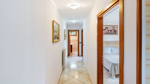 A hallway with a bed, a radiator, and framed pictures on the wall.