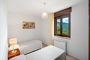 Ein Schlafzimmer mit zwei Betten, einem Bild, einem Fenster mit Blick und einer Lampe.