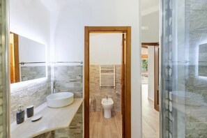 Une salle de bain moderne dotée d’un grand lavabo, d’un bidet et d’une douche à parois de verre.