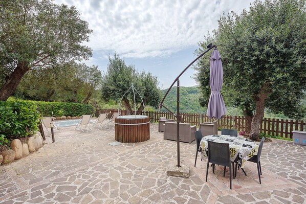 Une terrasse extérieure avec un sol en pierre, un jacuzzi et du mobilier d’extérieur.