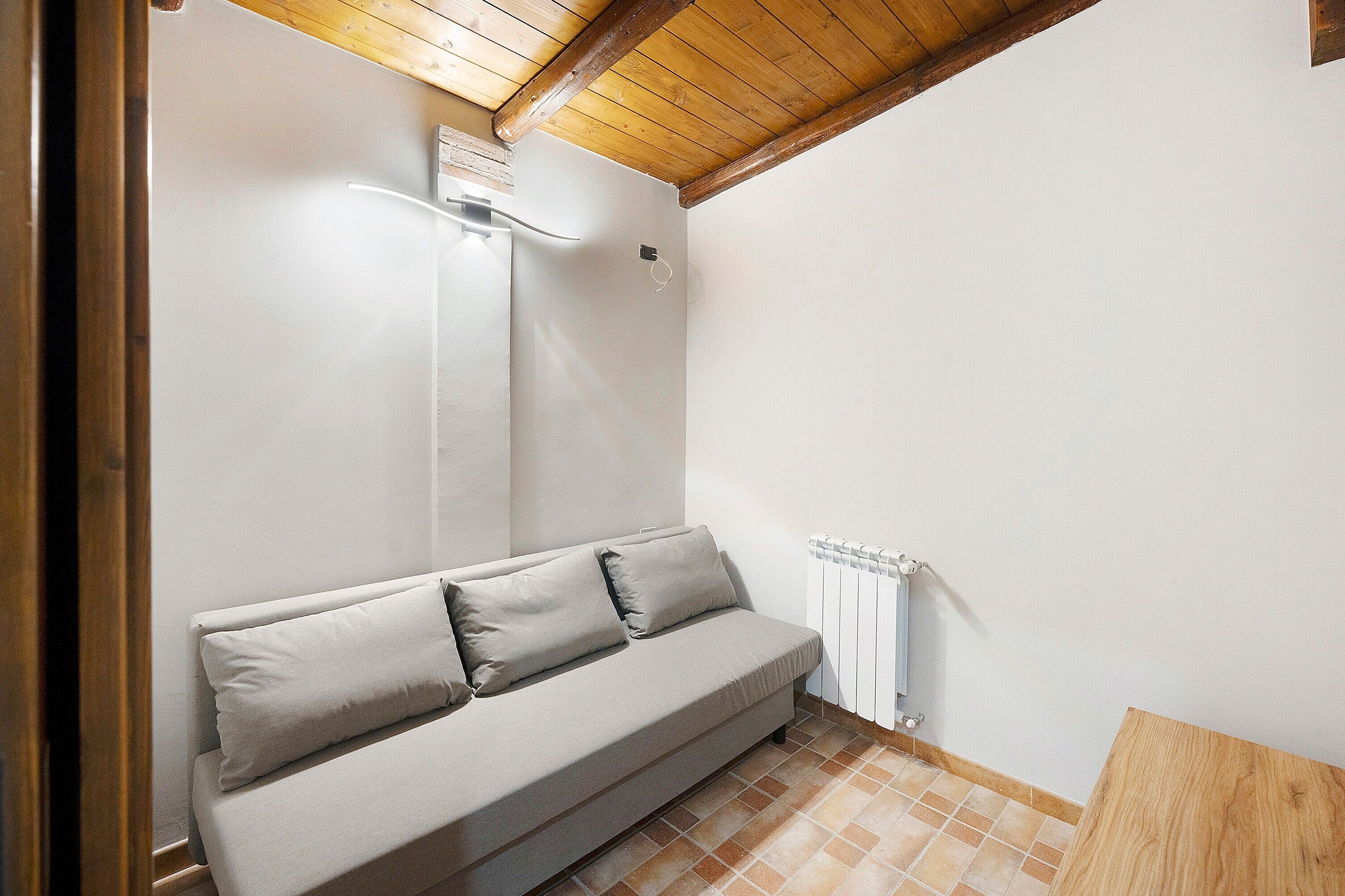 Une pièce avec un canapé, un radiateur et un plafond en bois.