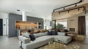 Un espacio habitable moderno con un amplio sofá modular en forma de L, una cocina con electrodomésticos integrados y un comedor con vistas.