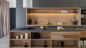 Una cocina moderna con una isla central, estantes de madera y horno empotrado.