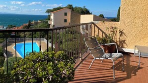 A balcony with a pool, two lounge chairs, and a view of the sea and buildings. - Collioure large apartment terrace swimming pool garage air-conditioning exceptional view. (Collioure)