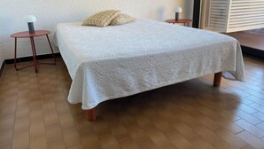 A bedroom with a bed, two bedside tables, and a window with blinds. - Collioure large apartment terrace swimming pool garage air-conditioning exceptional view. (Collioure)