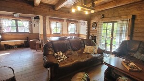 A cozy wooden cabin interior with a leather sofa, a wooden table, and a bench.