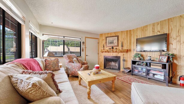 A cozy living room with a fireplace, wooden walls, a large TV, and a comfortable seating area.