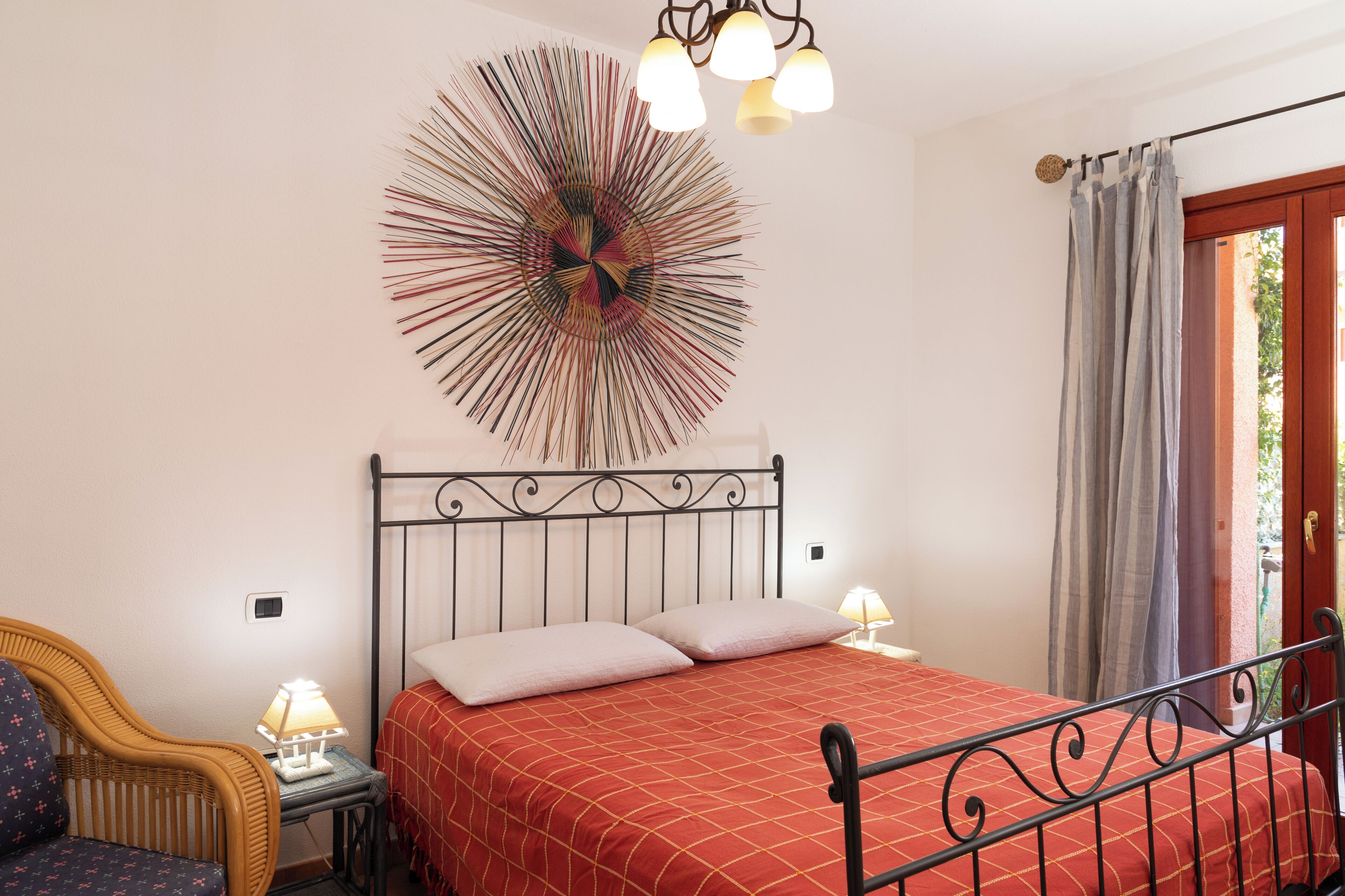 A bedroom with a bed, a chair, a lamp, and a wall art piece.