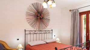 A bedroom with a bed, a chair, a lamp, and a wall art piece. - Casa Marzia by Wonderful Italy (Olbia)