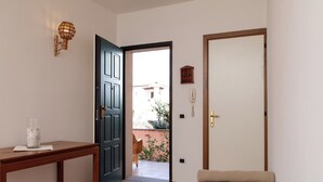 A bedroom with a bed, a wooden table with a glass container, a door, and a view of the outside. - Casa Marzia by Wonderful Italy (Olbia)