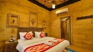 Una habitación de hotel con una cama grande, una mesita de noche, aire acondicionado en la pared y una puerta.