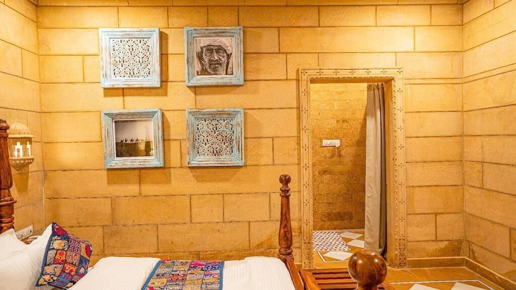 Una habitación con una cama, cabecera de madera, mesita de noche con lámpara y una pared decorada con cuatro cuadros.
