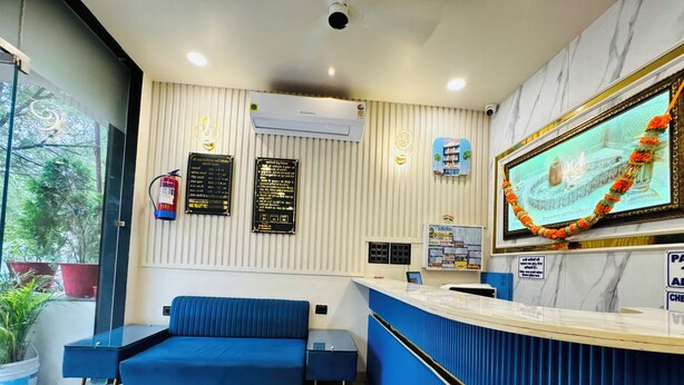 Ein Empfangsbereich mit einem blauen Sofa, einer gebogenen Rezeption und einem an der Wand montierten Fernseher.
