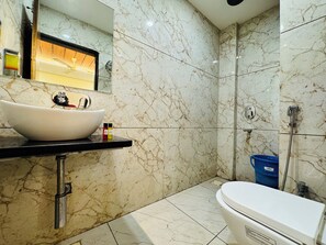 A bathroom with a white sink, mirror, and toilet.
