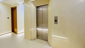 Ein moderner Aufzug mit Metalloptik, einem Bedienfeld und einer beige gefärbten Wand.