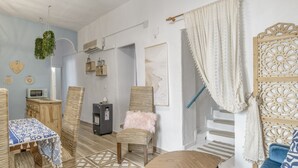 Ein Zimmer mit Holztisch, blauem Sofa, Stuhl mit flauschigem Kissen, Treppe und einer dekorativen Wandverkleidung.