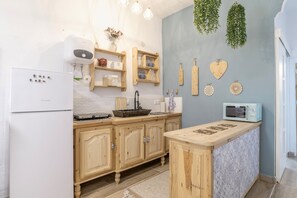 Eine Küche mit Holzausstattung, einem weißen Kühlschrank, einer Mikrowelle und dekorativen Wandbildern.