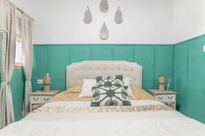 Ein Schlafzimmer mit einem Bett, Nachttischen, einem Fenster mit Vorhängen und Wandspiegeln.