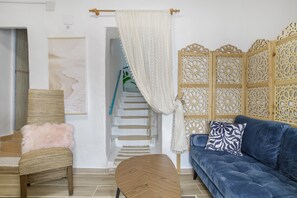 A living room with a blue sofa, a wooden chair with a fluffy pillow, a wooden coffee table, a staircase, and a decorative wooden partition. - Holiday Home 'Casa Bohemia' with Lake Views, Shared Terrace and Air Conditioning (Arcos de la Frontera)