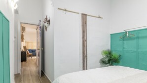 Ein Schlafzimmer mit einem Bett, einer grünen Tür, einer Vorhangstange und einer Pflanze.