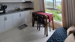 Una cocina compacta con armarios blancos y una zona de comedor con mesa y sillas.