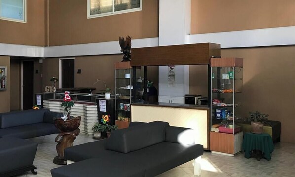 A lobby with a reception desk, a blue sofa, and a wooden bench. - Cozy Condo 700m Away From Burnham (Baguio)