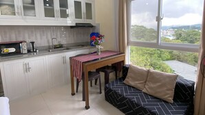Una cocina moderna con armarios blancos, una mesa de comedor con mantel a rayas y un sofá con funda estampada.