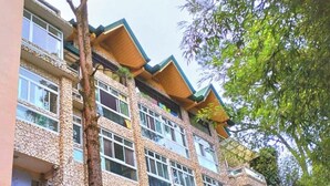 Un edificio de varios pisos con fachada de piedra, varios balcones y ventanas amplias.