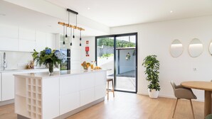 Eine moderne Küche mit weißen Schränken, einer zentralen Kochinsel und einem Essbereich mit Holztisch und Stühlen.