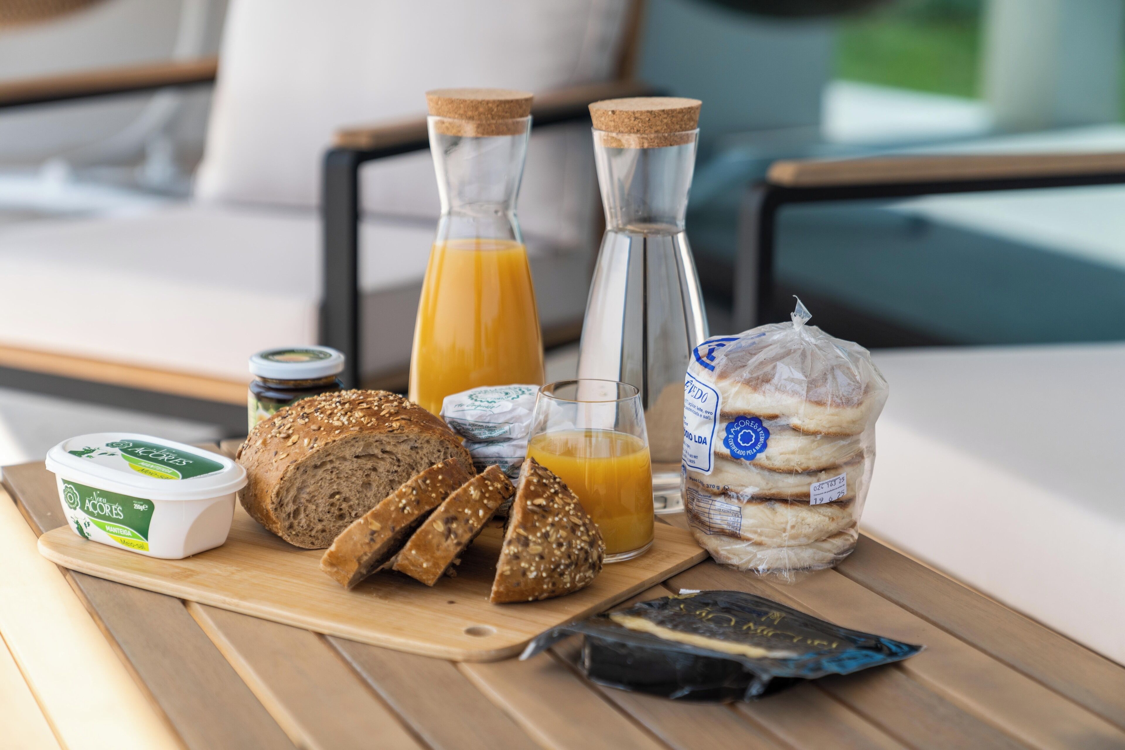 A breakfast setup with bread, juice, cheese, and yogurt on a wooden table.