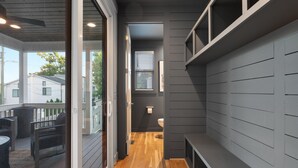 A modern interior with a wooden floor, grey walls, and a glass door leading to an outdoor patio area. - New Stunning 4BR Nashville Home | Rooftop • Shuffleboard • Mural • Designer Interiors (Nashville)