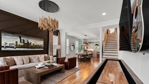A modern living room with a sofa, coffee table, and a billiard table. - New Stunning 4BR Nashville Home | Rooftop • Shuffleboard • Mural • Designer Interiors (Nashville)
