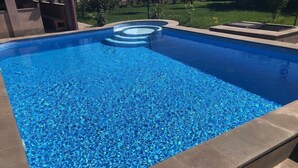 Une piscine rectangulaire à l’eau d’un bleu limpide, entourée d’une terrasse en pierre.
