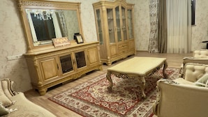 Un vaste salon agrémenté d’une grande armoire décorative, d’un canapé assorti et d’un lustre.
