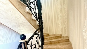 Un escalier orné de rampes en métal noir et doté d’un sol en marbre.