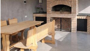 Une cuisine moderne avec un four en briques, une table à manger avec des bancs et un mur gris.
