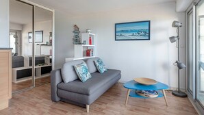 A modern living room with a grey sofa, a small round table, and a bookshelf. - Seafront, apartment for 4 people (Pornic)