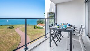 A balcony with a dining table, chairs, and a view of the sea. - Seafront, apartment for 4 people (Pornic)